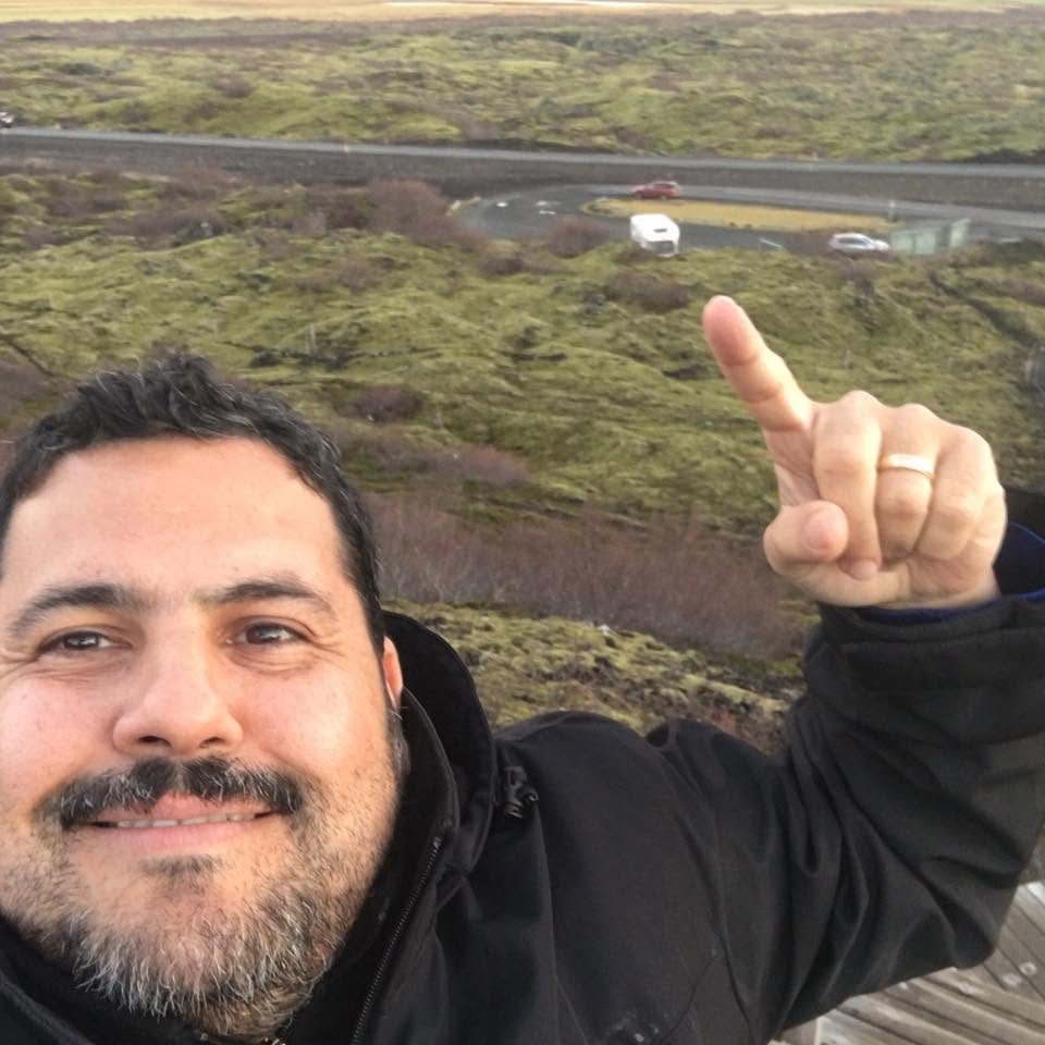 Juan taking a selfie and pointing at the view behind him